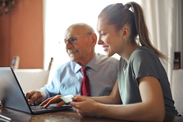 Yngre kvinna och äldre man framför dator